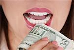 Close-up of a businesswoman holding a bundle of dollar bills near her mouth