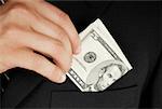 Mid section view of a businessman putting dollar bills in his pocket