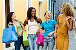 Four teenage girls holding shopping bags and laughing