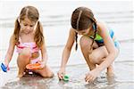 Close-up of two girls playing with toys on the beach