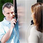 Close-up of a mid adult couple talking on a pay phone