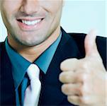 Gros plan d'un homme d'affaires montrant thumbs up signe et souriant