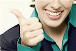 Close-up of a businesswoman showing thumbs up sign and smiling