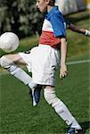 Side profile of a soccer player balancing a soccer ball on his thighs