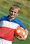 Portrait d'un joueur de football, tenant un ballon de soccer et souriant