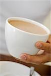 Gros plan de la main d'une personne tenant une tasse de café