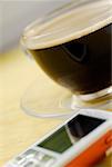 Close-up of a cup of black coffee and a mobile phone