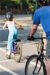 Rear view of a man and a girl cycling