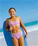 Portrait d'une jeune fille tenant une planche de surf, debout sur la plage, Bermudes