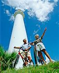 Low angle view of a senior couple standing in front of a tower with their bicycles, Bermuda