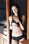 Portrait of a young woman in lingerie dipping a teabag in a cup of tea