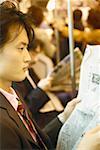 Side profile of a businessman reading a newspaper in the train