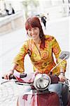 Portrait of a young woman sitting on a motor scooter and smiling