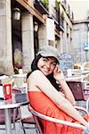 Side profile of a mid adult woman sitting at a sidewalk cafe