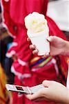 Close-up of a woman's hands holding an ice-cream and using a mobile phone
