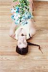 High angle view of a young woman lying on the floor and holding up a bunch of flowers