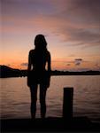 Silhouette of a young woman standing on a pier