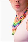Close-up of a gay man wearing a colorful necklaces and puckering his lips