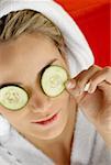 High angle view of a young woman resting with cucumber slices on her eyes