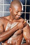 Close-up of a young man applying soap on his body