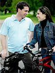 Mid adult couple standing with their bicycles and looking at each other