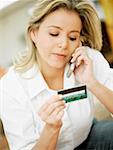 Close-up of a mid adult woman talking on a mobile phone and holding a credit card