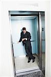 Businessman standing in an elevator and looking at his wristwatch