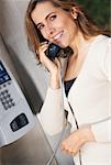 Portrait of a mid adult woman talking on a pay phone and smiling