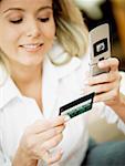 Close-up of a mid adult woman holding a mobile phone and a credit card