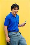 Portrait d'un jeune homme tenant un téléphone portable et souriant