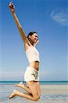 Side profile of a young woman jumping on the beach