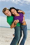 Portrait d'un jeune couple de danse sur la plage et souriant