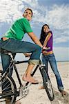 Gros plan d'un jeune homme assis sur un vélo avec une jeune femme à côté de lui