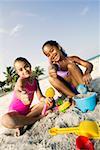 Portrait of two girls playing with sand on the beach