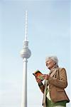 Tourist Looking at Guidebook in Front of the Fernsehturm, Berlin, Germany