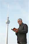 Tourist Looking at Guidebook in Front of the Fernsehturm, Berlin, Germany