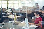 Woman Using Laptop in Restaurant