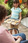 Grand-mère montrant petite-fille plateau de biscuits maison