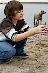 Boy Looking at Stone on Beach