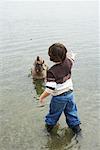 Jungen spielen mit Hund am Strand