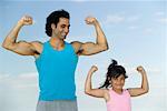 Portrait of Father and Daughter Flexing Muscles