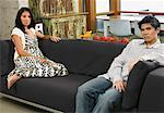 Couple assis sur le canapé à la maison