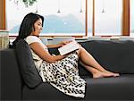 Woman Sitting on Sofa Reading Book