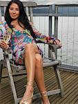 Portrait of Woman Sitting on Deck by Ocean Drinking Wine