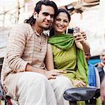 Young couple sitting in a rickshaw and taking a photograph of themselves