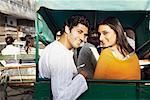 Portrait of a young couple sitting in a rickshaw and smiling