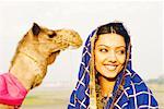 Close-up of a young woman with a camel in the background