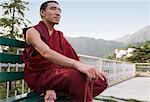 Monk sitting on the bench and holding prayer beads, McLeod Ganj Dharmakot, Dharamshala, Himachal Pradesh, India