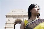 Low angle view of a young woman in front of a monument, India Gate, New Delhi, India