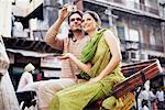 Young couple sitting in a rickshaw and taking a photograph